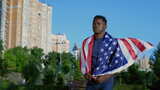 爱国者非裔美国人走在夏天背上插着美国国旗的街上高清在线视频素材下载