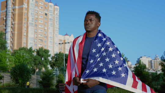 爱国者非裔美国人走在夏天背上插着美国国旗的街上