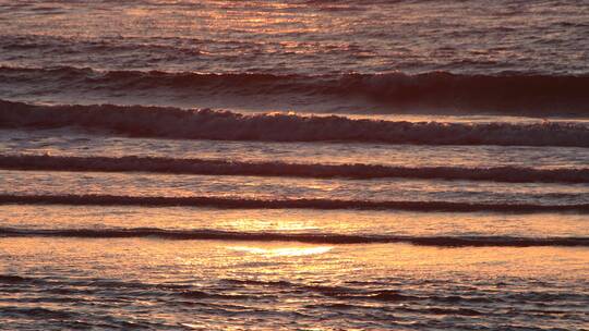 落日余晖映照的金色海面波浪