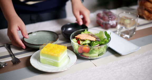 年轻女子准备杯子和盘子，把食物放在家里的