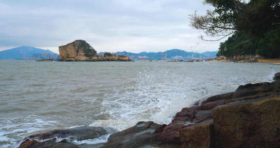 海边岩石处海浪拍打溅起白色浪花