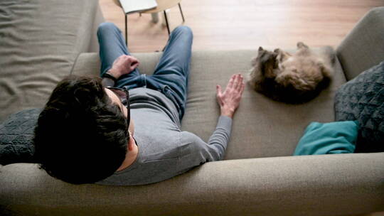 和猫咪坐在沙发上的男士