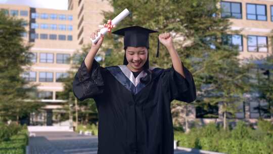 学生手持文凭在大学门前跳舞庆祝毕业