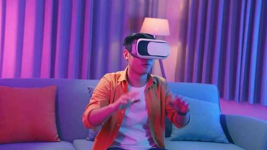 年轻的亚洲男子在客厅探索虚拟现实，青色和