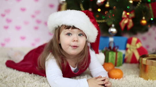戴着圣诞帽躺在地毯上的小女孩
