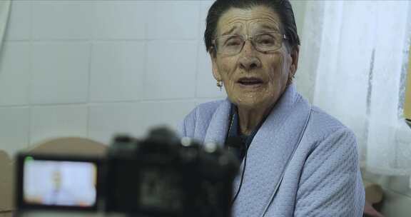 老年妇女在摄像机上说话和录音