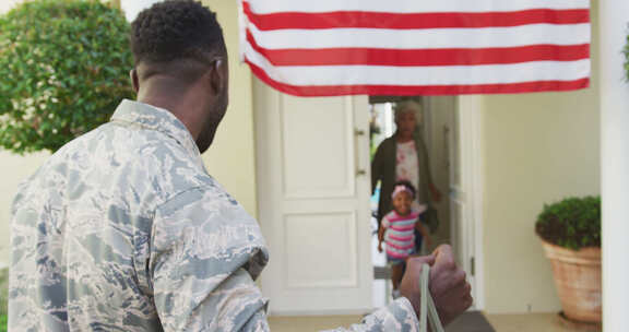 非裔美国男士兵在美国国旗上拥抱他微笑的女儿