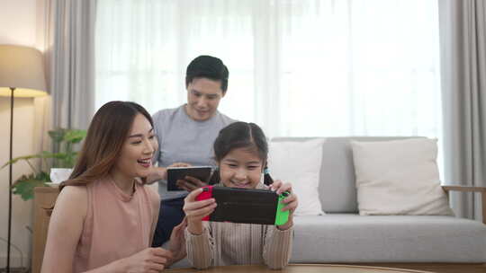 女儿正在家里和父母一起玩电子游戏。