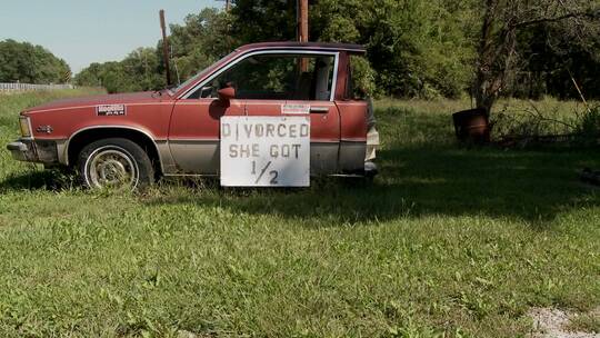 草坪上的一半汽车上贴着离婚分到二分之一汽车的标牌