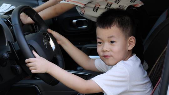 孩子坐在汽车驾驶座上假装开车游戏