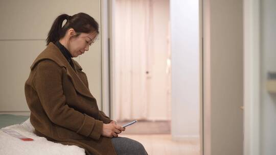 寂寞中年女性情绪低落坐在床上使用手机