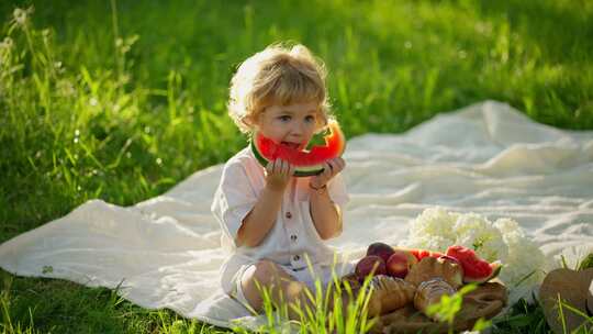 可爱的小女孩在吃西瓜做在草地上
