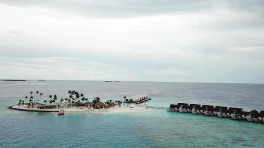 无人机在马尔代夫一个度假胜地的水上别墅岛上空飞行。蓝色和绿松石色的水。4K