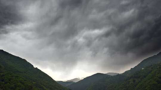 厚厚的黑色云层覆盖着森林山脉之间的山谷视频素材模板下载