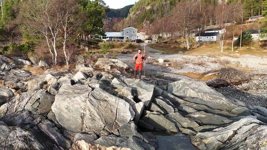 橙色徒步旅行者站在泡沫海浪中的海岸岩石上