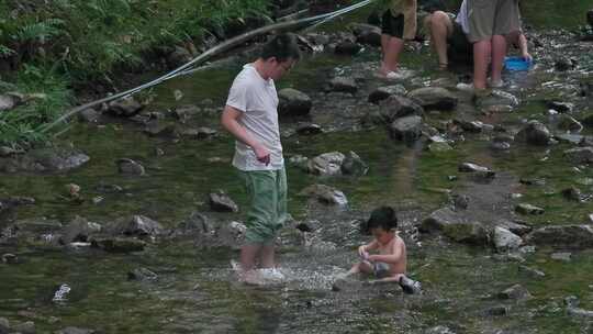 大人小孩在布满石头的溪流中玩水