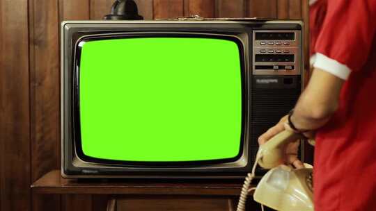 十几岁的男孩在旧电话上说话，看着复古电视绿屏。视频素材模板下载