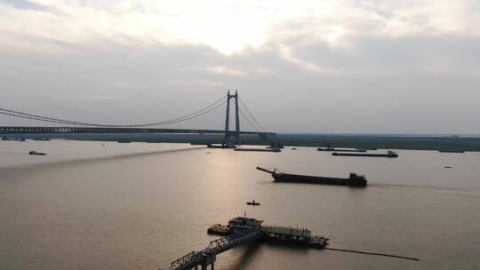 航拍夕阳下的城市跨河大桥轮船划过