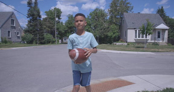 小男孩在街上玩橄榄球
