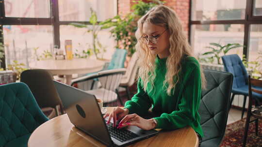 戴眼镜的漂亮女人在咖啡馆的笔记本电脑上打字通过免费Wifi上网肖像