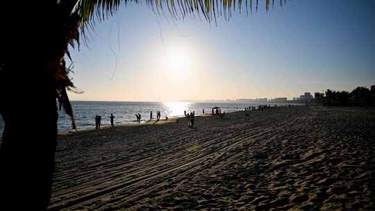 海南三亚黄昏阳光下沙滩度假的人群剪影