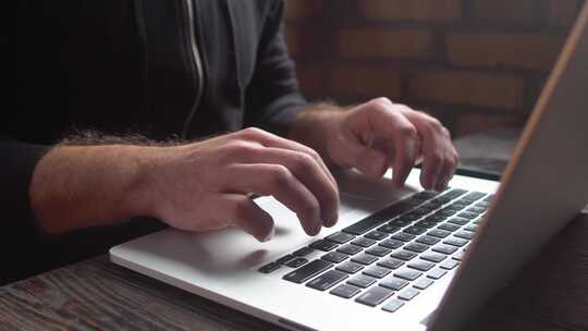 阁楼咖啡馆里，男人在笔记本电脑键盘上打字。特写男人双手在笔记本电脑键盘上写字。视频素材模板下载