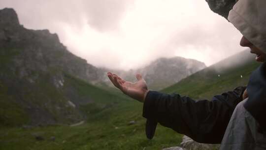 在山顶石洞伸手接雨的男子