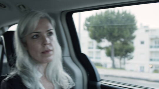 坐在汽车后座的银发女人到处张望