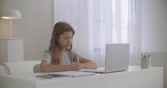 女孩在家里用笔记电脑做家庭作业