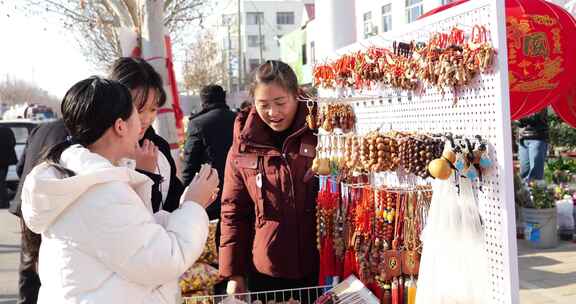 户外摊位前顾客挑选饰品的场景