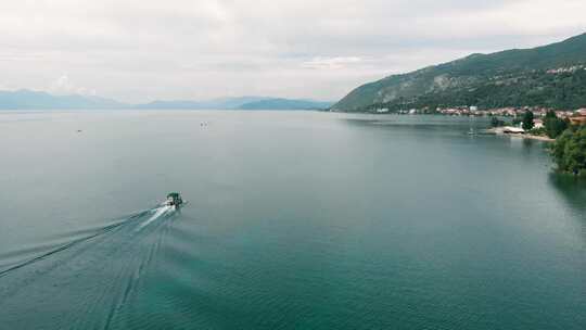 航拍跟随船在麦克多尼亚的奥赫里德湖，可以看到海岸、悬崖和美丽的蓝色水域