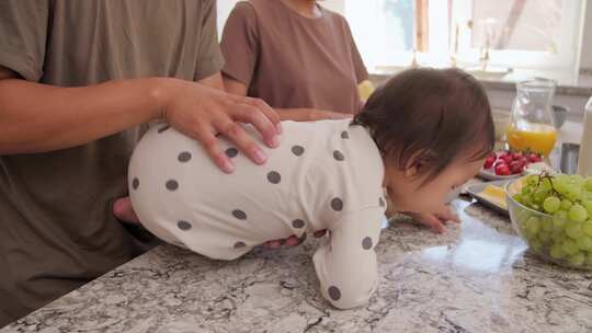 蹒跚学步的孩子在厨房柜台上和爸爸妈妈触摸