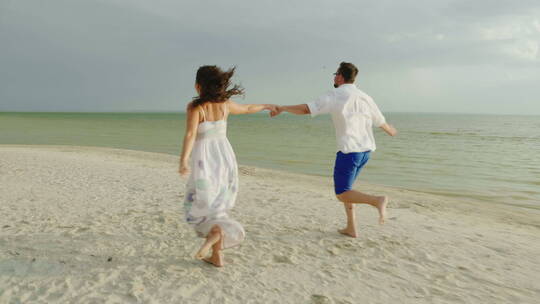 年轻夫妇手牵手在海滩上奔跑