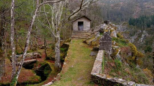 山间小屋，石墙在悬崖上，有一座桥和圆周率的木桌
