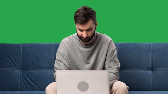 男人远程工作笔记本电脑聊天浏览互联网沙发隔离绿屏色度键视频素材模板下载