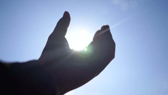 手握阳光穿过指缝手握住拳头伸手遮住太阳光