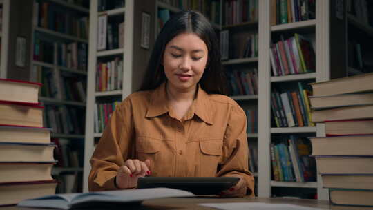 大学图书馆中的亚裔女女学生使用数字平板电