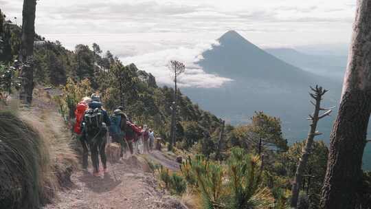 徒步旅行者走在土路上，在雾中观看山顶