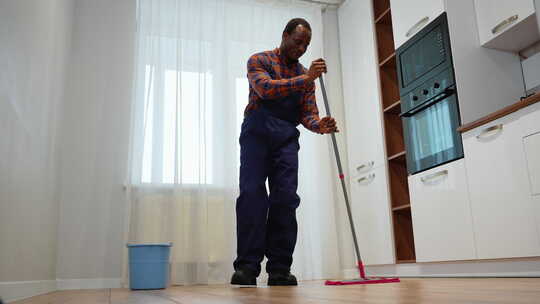 有趣的黑色开朗的专业清洁工在洗地板时用拖视频素材模板下载