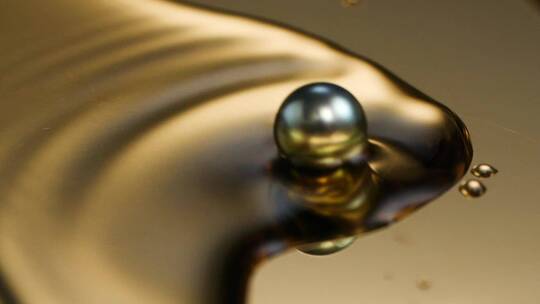 一颗黑珍珠在在金色盘子滚入水中