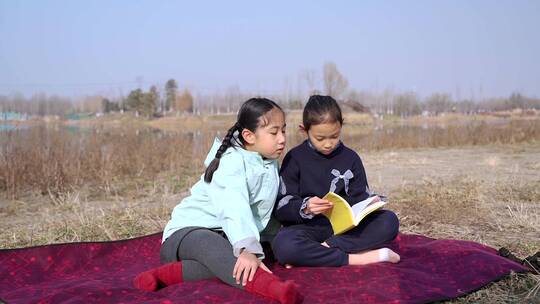 冬季在公园草坪上看书的两个女孩