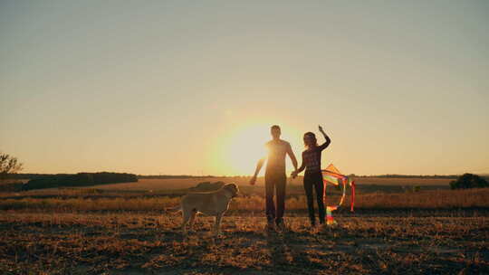 美丽的年轻夫妇带着狗带着风筝跑步
