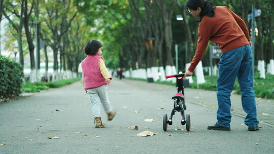 顽皮的小女孩和妈妈在公园路上骑车
