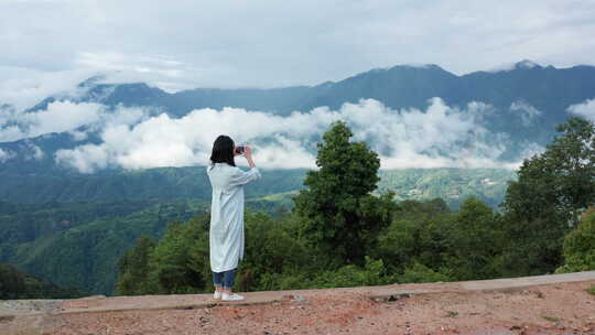 用手机拍摄云雾缭绕山川美景的少女