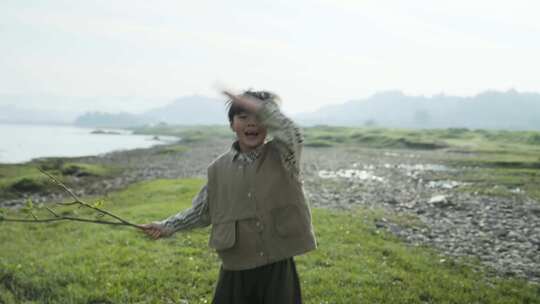 小男孩在河边草地上开心地奔跑