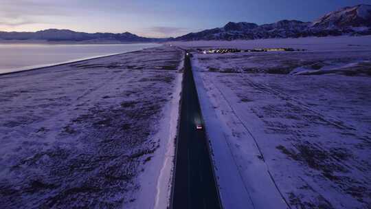 傍晚行驶在雪地公路的汽车