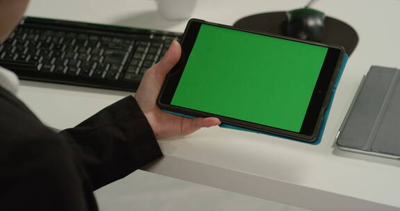 拿着绿色屏幕的平板电脑的女人
