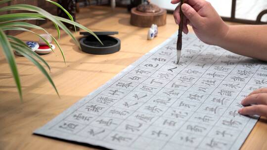 用字帖练习毛笔字的亚裔男性手部特写