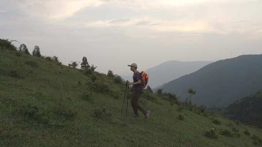 男子持登山杖在山腰上徒步前行