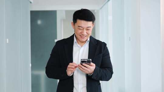 年轻成功的韩国商人正在用他的智能手机发短信